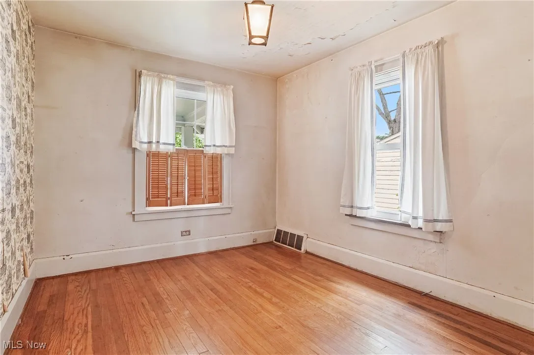 Spare room featuring wood-type flooring and plenty of natural light