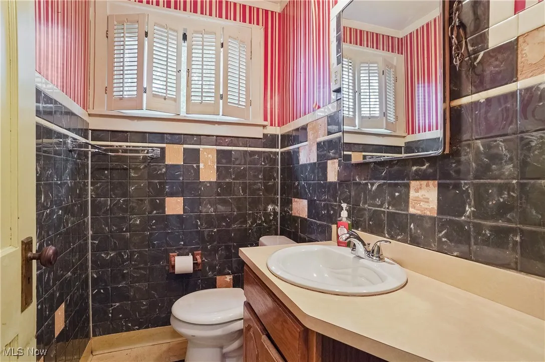 Full bathroom with tile walls, vanity, plenty of natural light, crown molding, and a shower