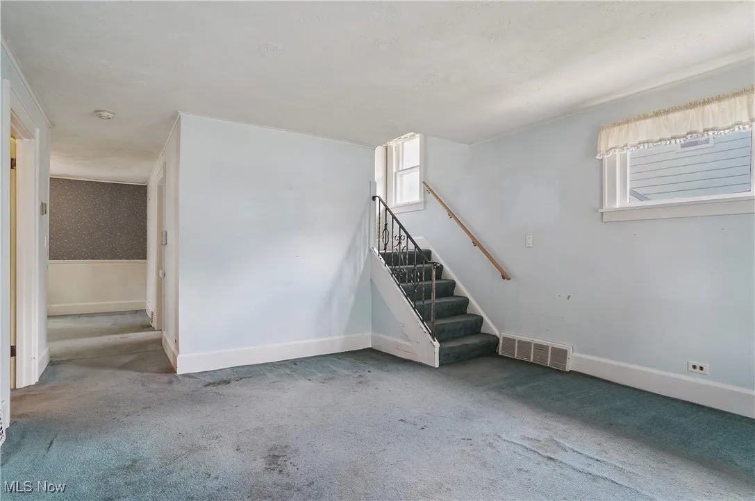 Below grade area with carpet flooring, healthy amount of natural light, and stairs
