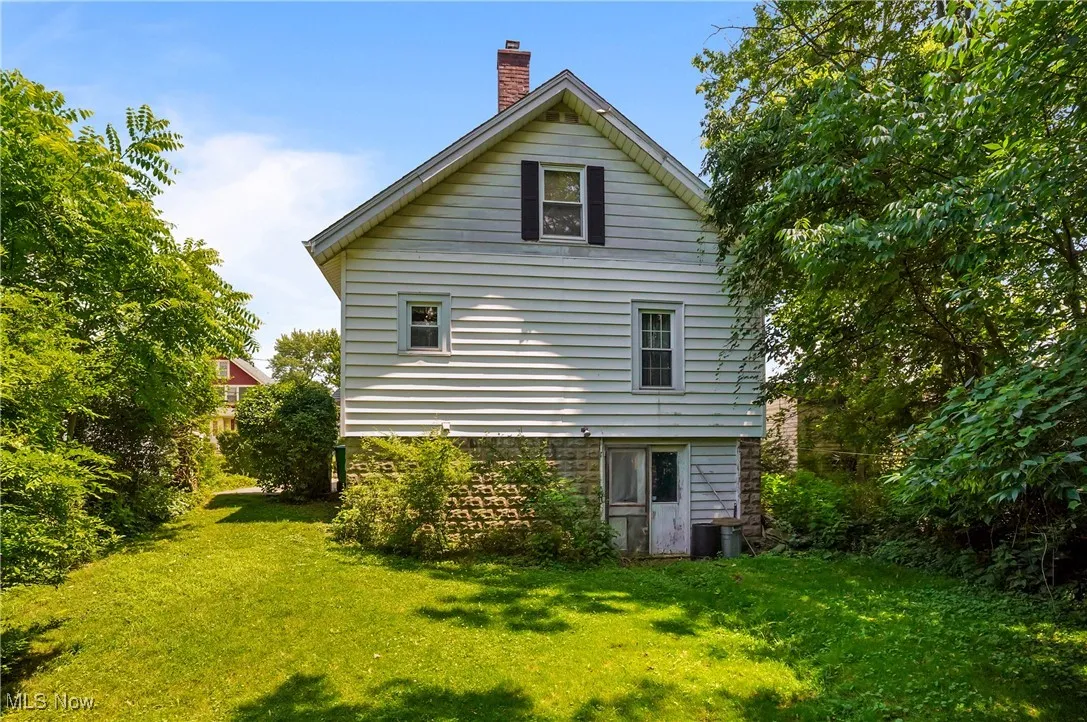 View of property exterior with a chimney and a yard