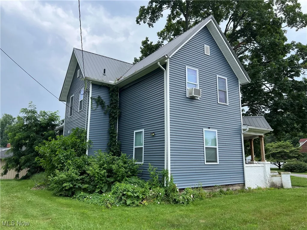View of side of home featuring a yard and a metal roof