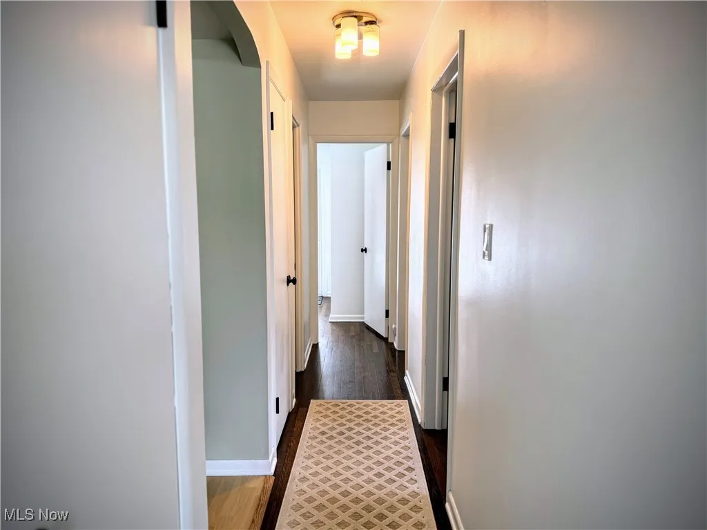 Hallway featuring baseboards and dark wood-style flooring
