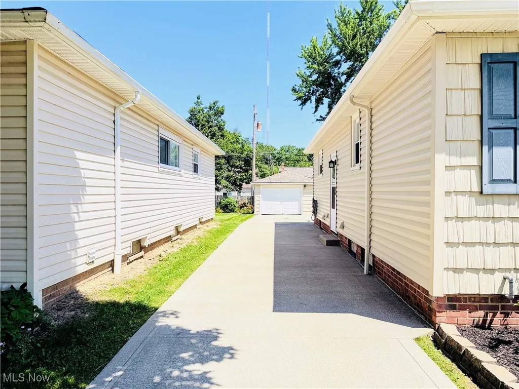 View of side of home with driveway, a detached garage, crawl space, and an outdoor structure