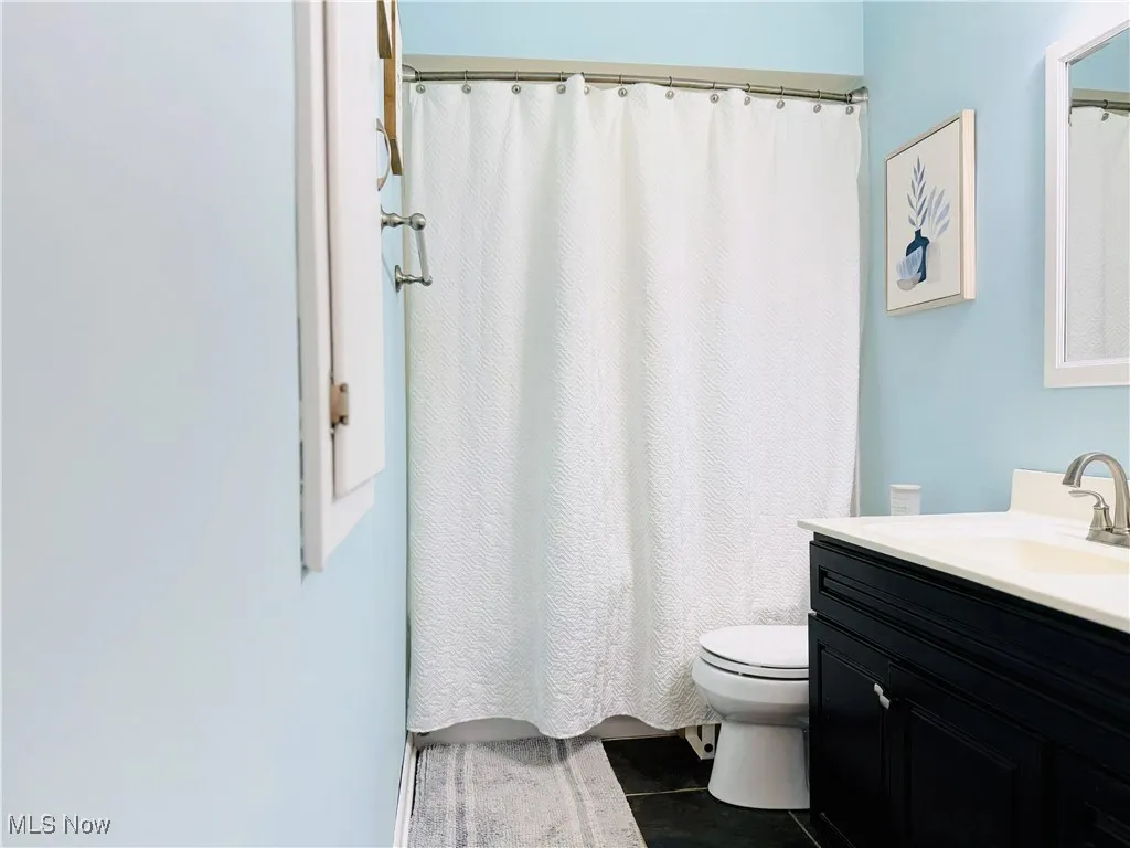 Bathroom featuring tile patterned floors, vanity, and curtained shower