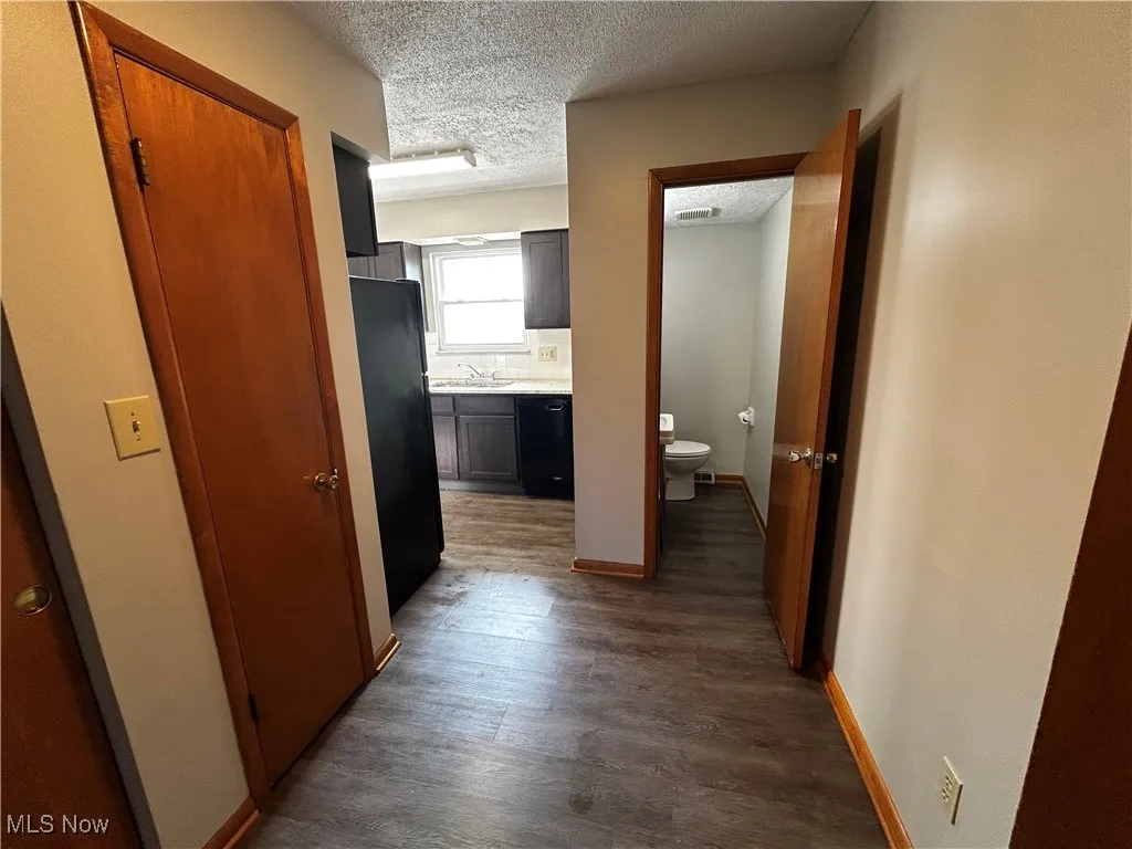 Corridor featuring a textured ceiling and wood finished floors