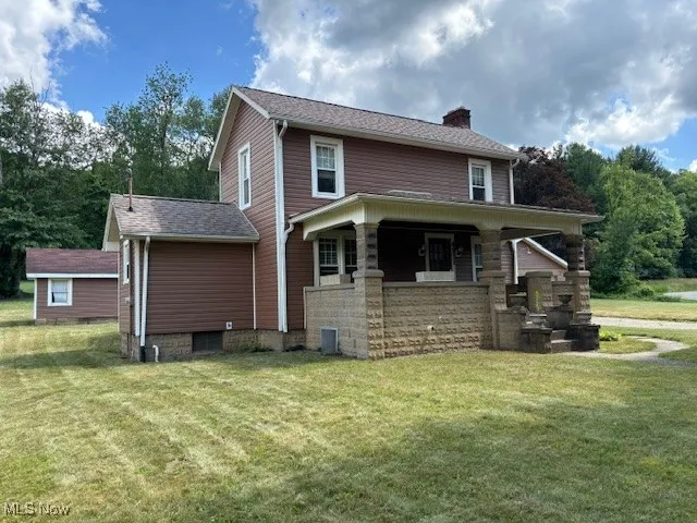 View of front of home featuring a chimney, a front yard, and covered porch