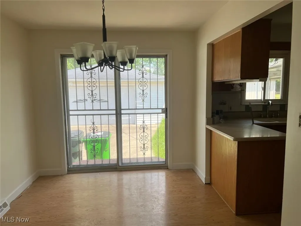 Unfurnished dining area featuring a chandelier and light wood-style floors
