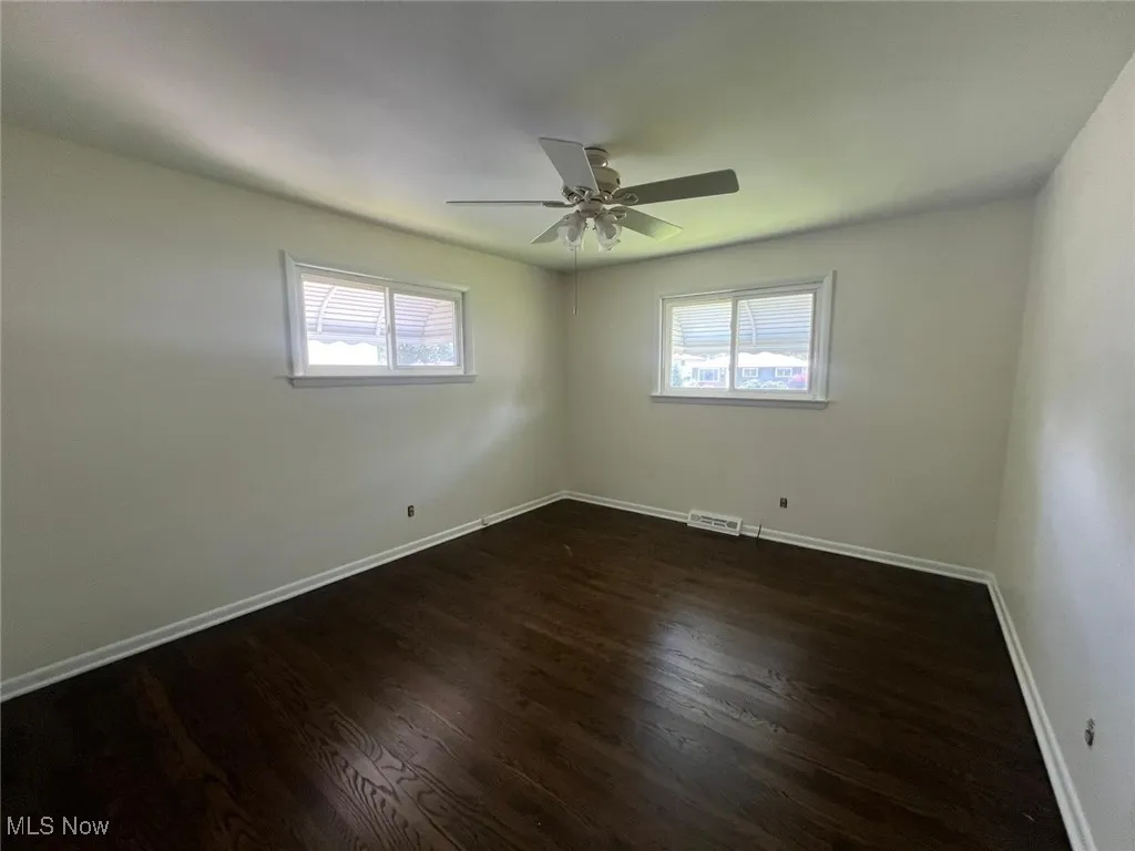 Unfurnished room featuring plenty of natural light, dark wood-type flooring, and ceiling fan