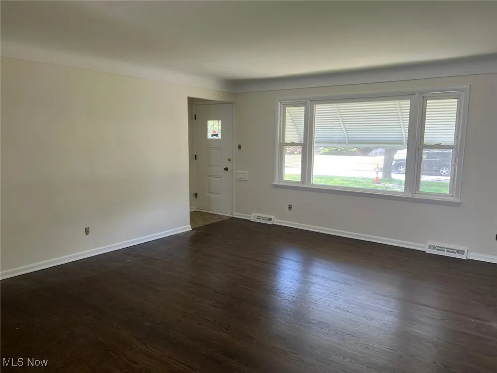 Spare room with dark wood-style flooring and baseboards