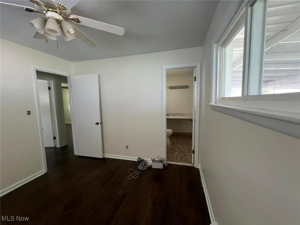 Unfurnished bedroom with wood finished floors, ensuite bathroom, and ceiling fan