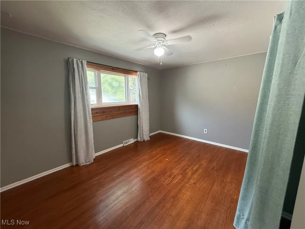 Unfurnished room featuring wood finished floors, a ceiling fan, and a textured ceiling