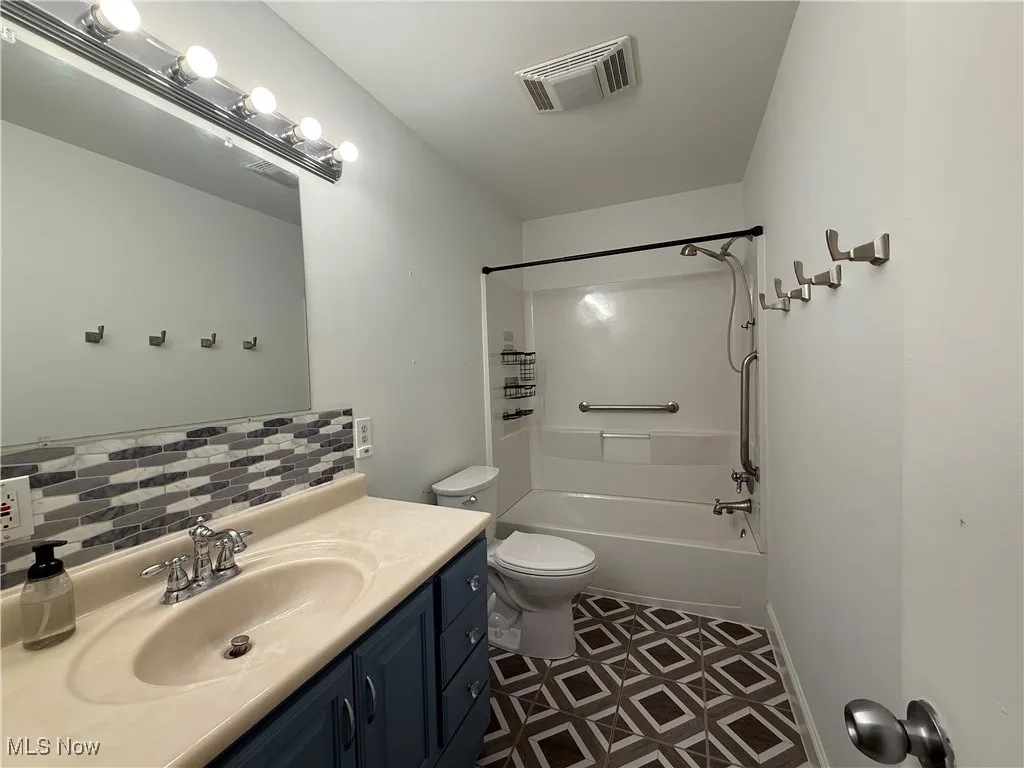 Bathroom featuring vanity, shower / bath combination, backsplash, and tile patterned floors