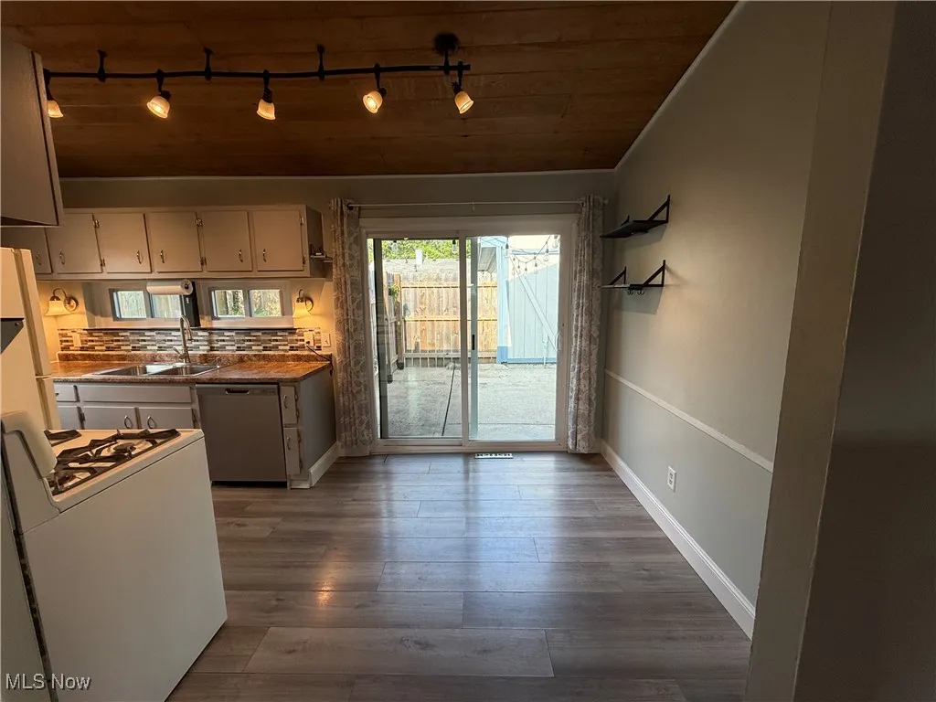 Kitchen featuring rail lighting, stainless steel dishwasher, white range with gas cooktop, wood ceiling, and white cabinetry