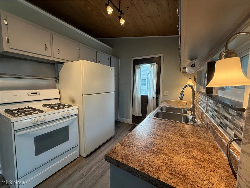 Kitchen featuring white appliances, dark wood finished floors, and wooden ceiling