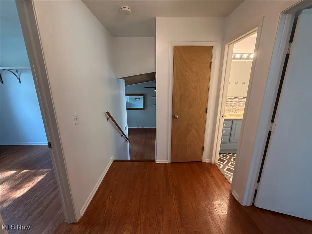 Corridor with an upstairs landing and wood finished floors