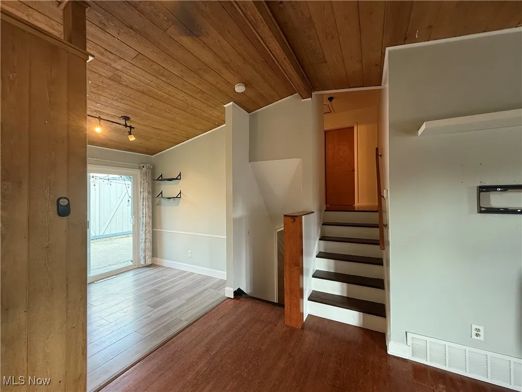Stairway with wooden ceiling, wood finished floors, and rail lighting