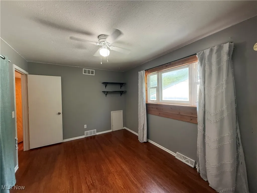 Spare room with wood finished floors, a ceiling fan, and a textured ceiling