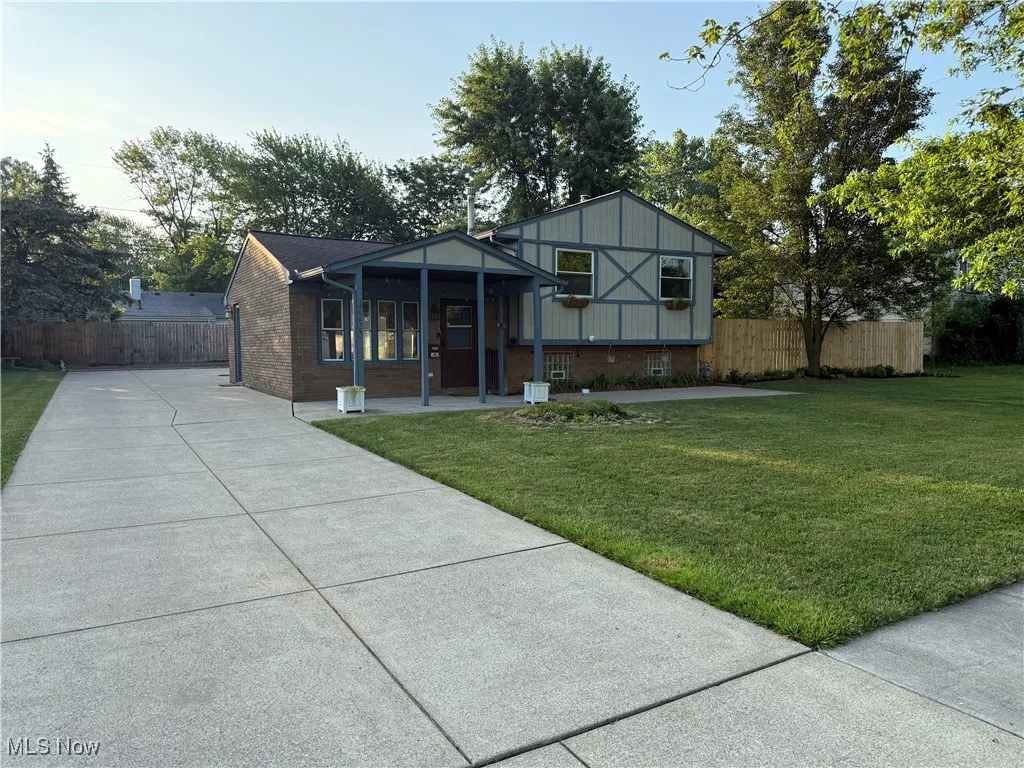 View of front of property with brick siding, covered porch, and concrete driveway