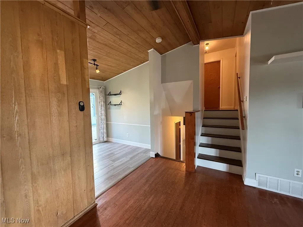 Staircase with wooden ceiling and wood finished floors