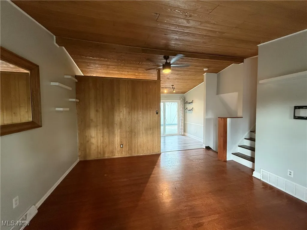 Unfurnished room featuring wood ceiling, a ceiling fan, wood finished floors, lofted ceiling, and stairs