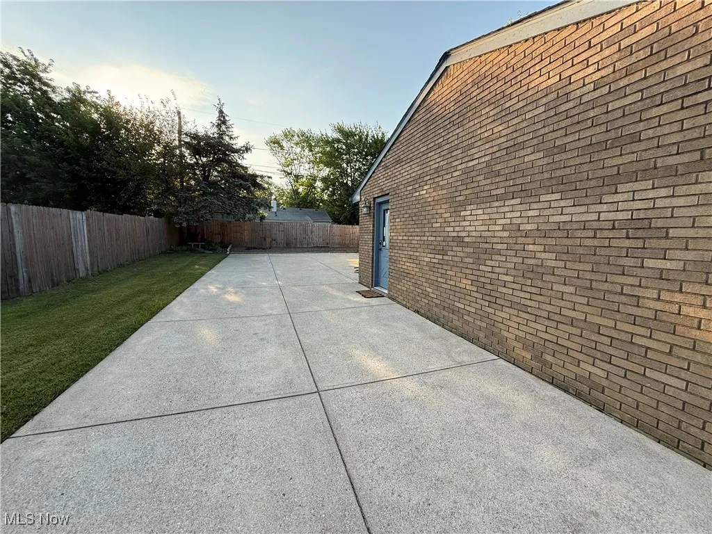 View of side of home featuring a fenced backyard, a patio area, and brick siding