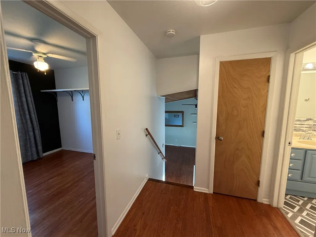 Corridor with an upstairs landing and wood finished floors