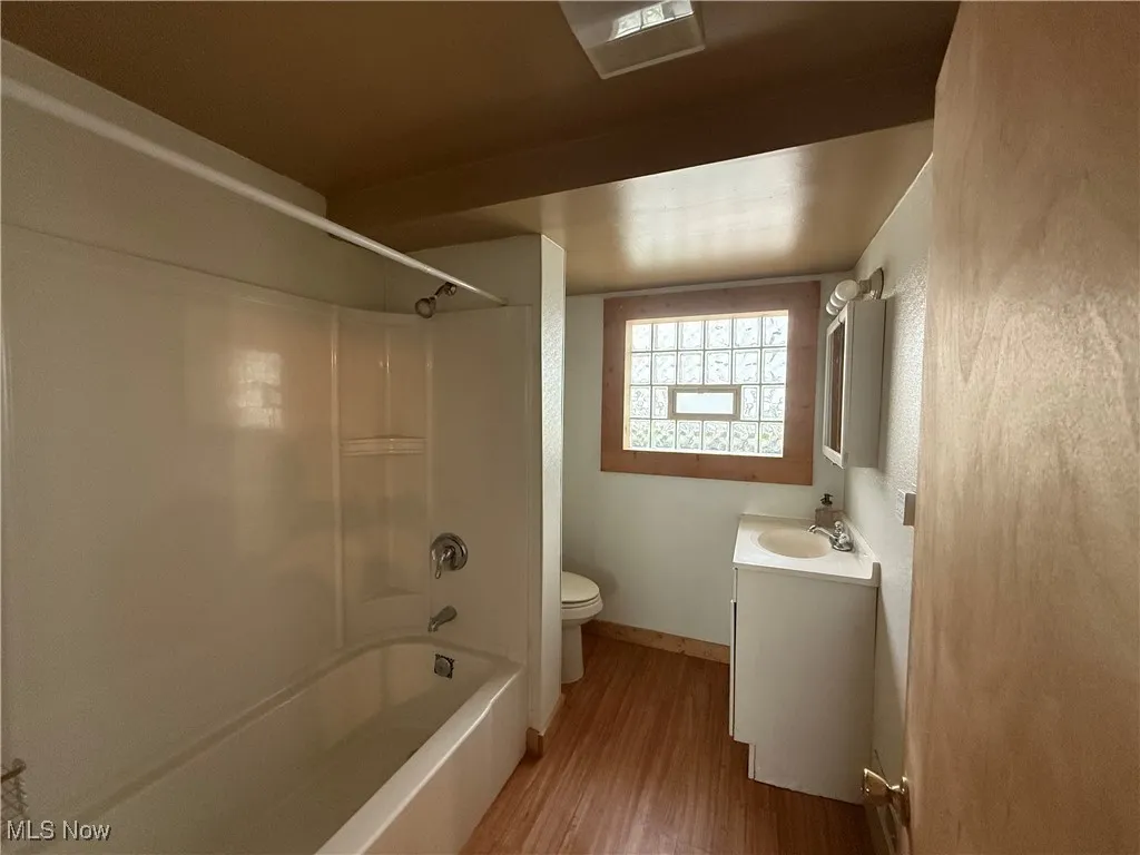 Bathroom with wood finished floors, vanity, and bathing tub / shower combination