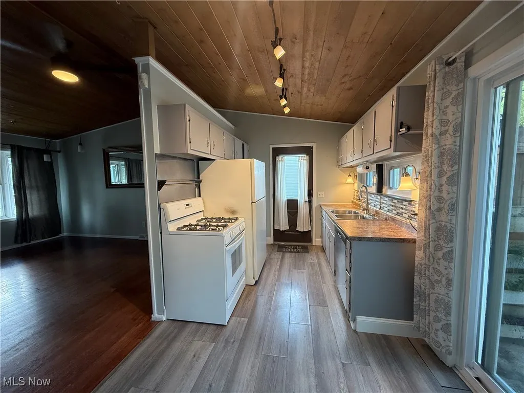 Kitchen with white appliances, wooden ceiling, wood finished floors, rail lighting, and decorative backsplash
