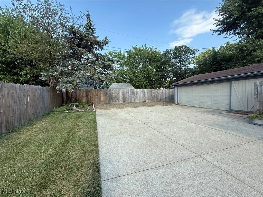 Fenced backyard featuring a garage and an outdoor structure