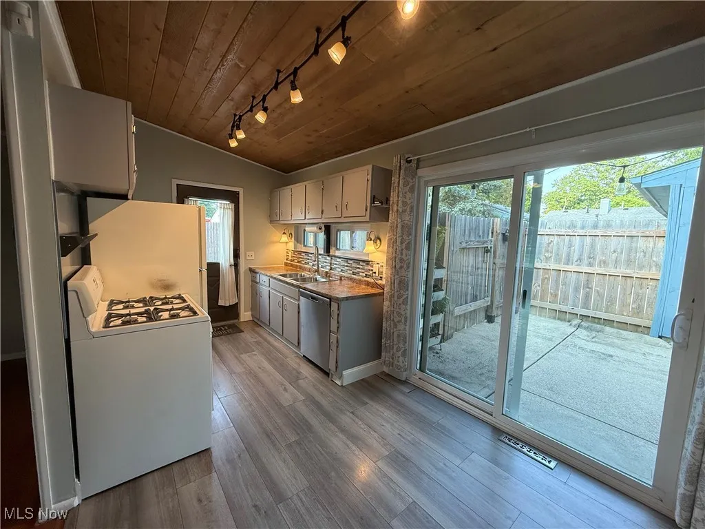 Kitchen featuring white appliances, track lighting, wooden ceiling, wood finished floors, and vaulted ceiling