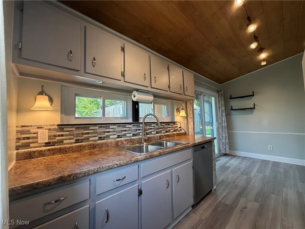 Kitchen featuring dishwasher, wood ceiling, decorative backsplash, dark wood finished floors, and dark countertops