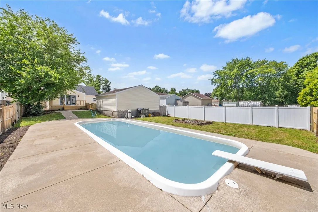View of swimming pool featuring a fenced backyard, a patio, a diving board, and a residential view