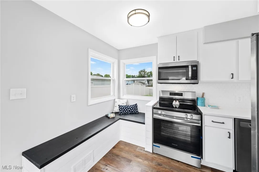 Kitchen featuring stainless steel appliances, dark wood-type flooring, and white cabinets