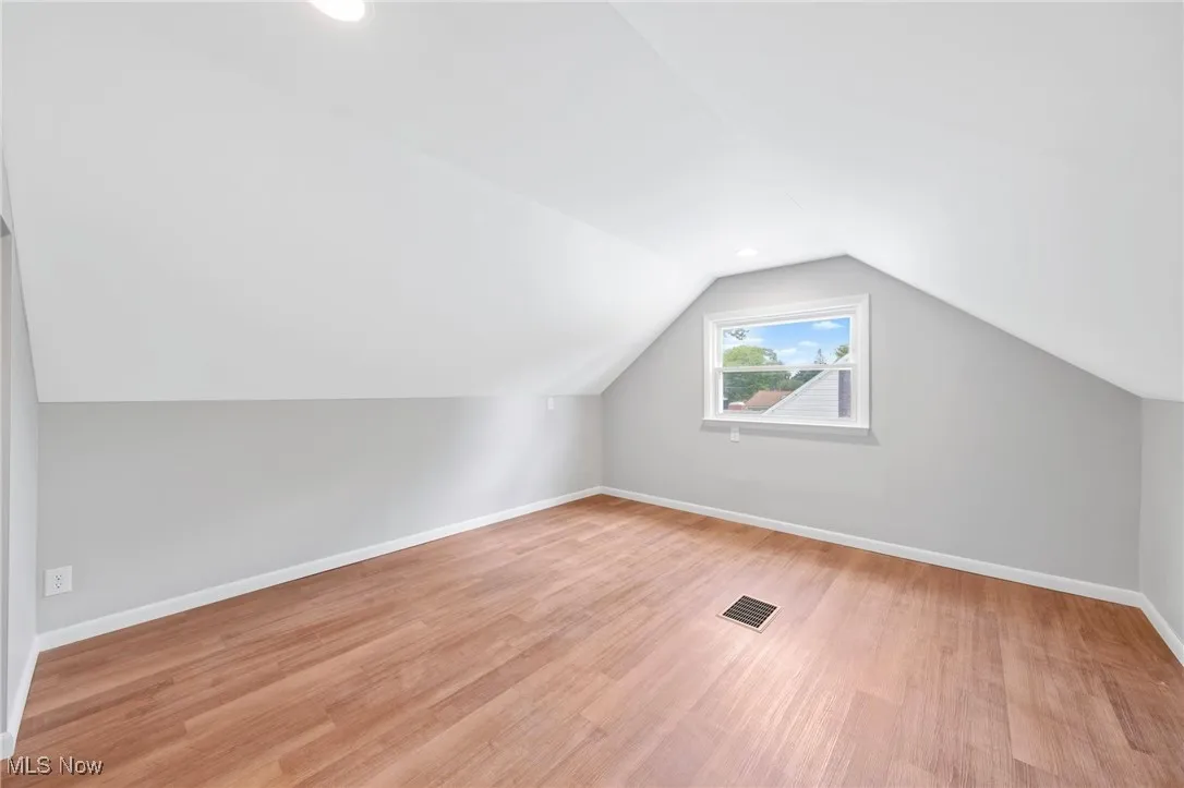 Additional living space featuring light wood-style flooring and vaulted ceiling