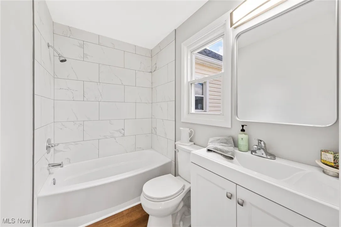 Bathroom featuring vanity, bathtub / shower combination, and wood finished floors