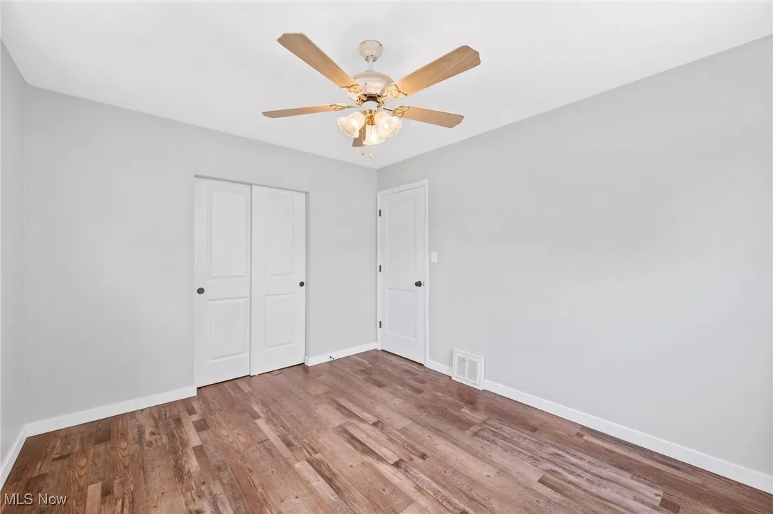 Unfurnished bedroom featuring wood finished floors, a closet, and ceiling fan