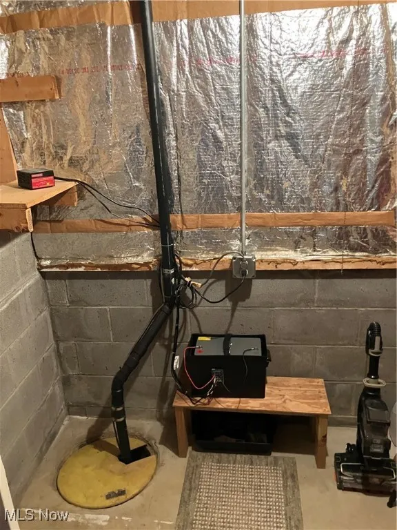 Basement view of concrete block wall, unfinished concrete flooring, and drainage system