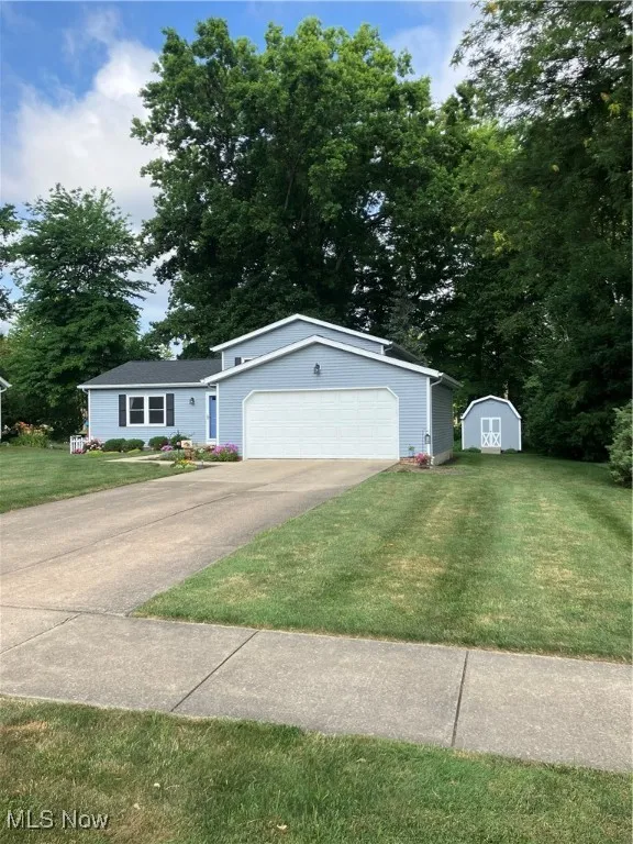 Ranch-style house with a front lawn, a garage, and a shed