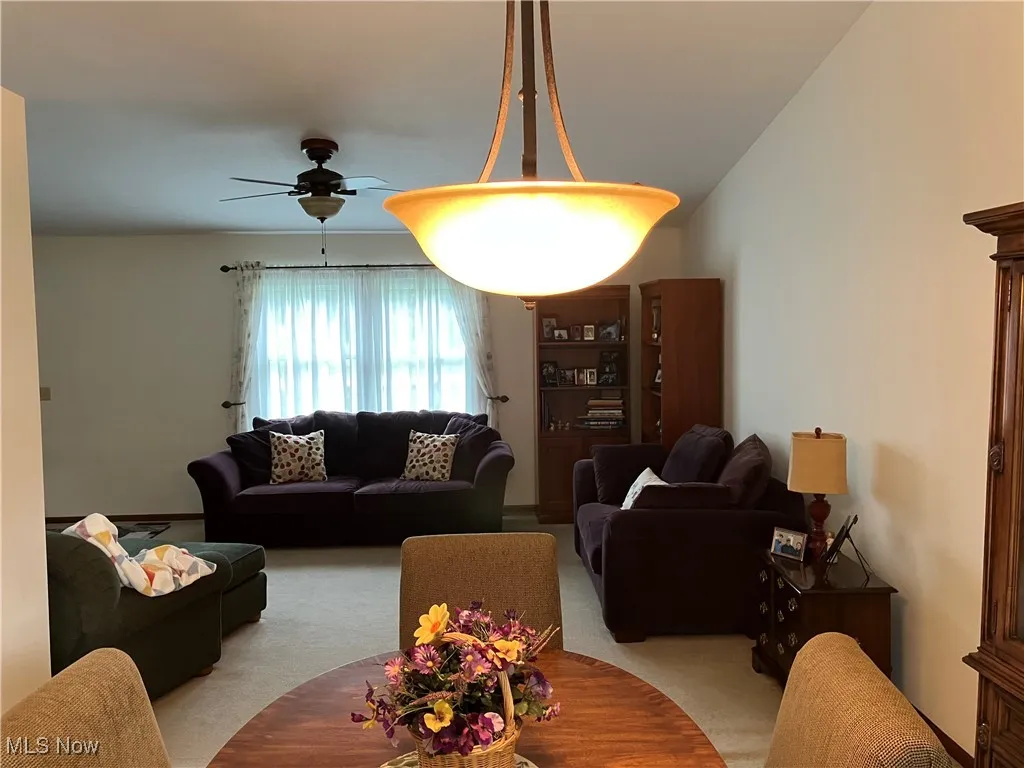 Carpeted living area with a ceiling fan