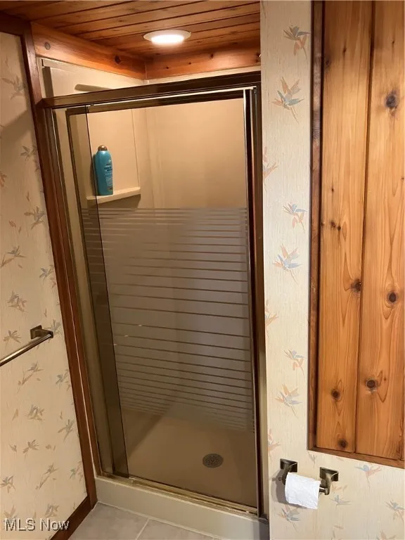 Full bathroom featuring a shower stall, tile patterned floors, wallpapered walls, and wood ceiling
