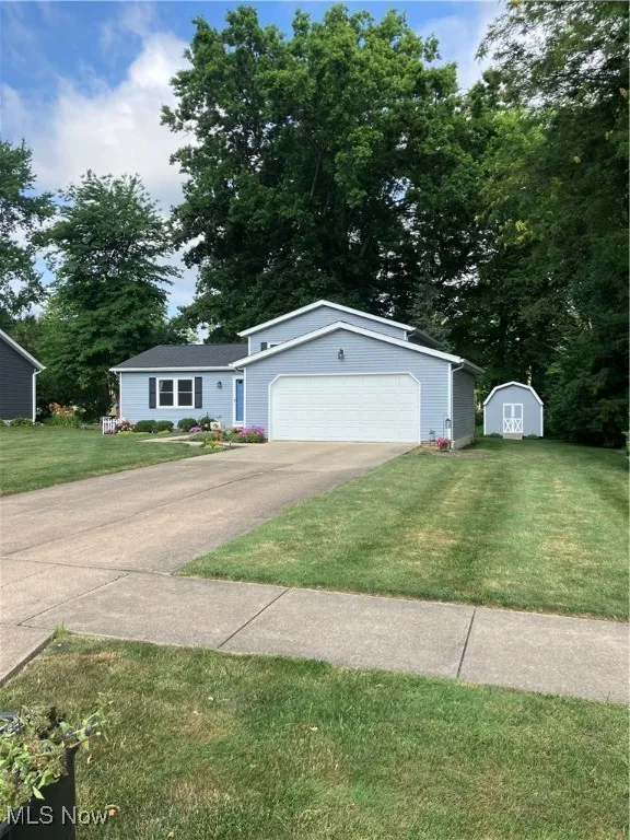 Single story home with a storage unit, a garage, and a front lawn