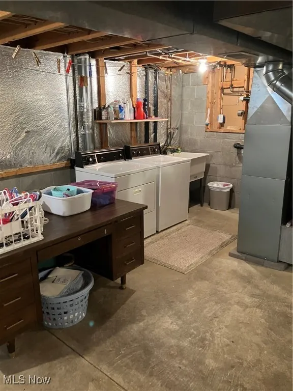 Unfinished basement featuring washer and clothes dryer and heating unit