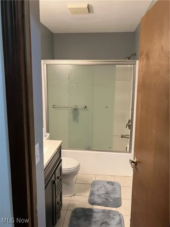 Bathroom with vanity, tile patterned floors, and enclosed tub / shower combo