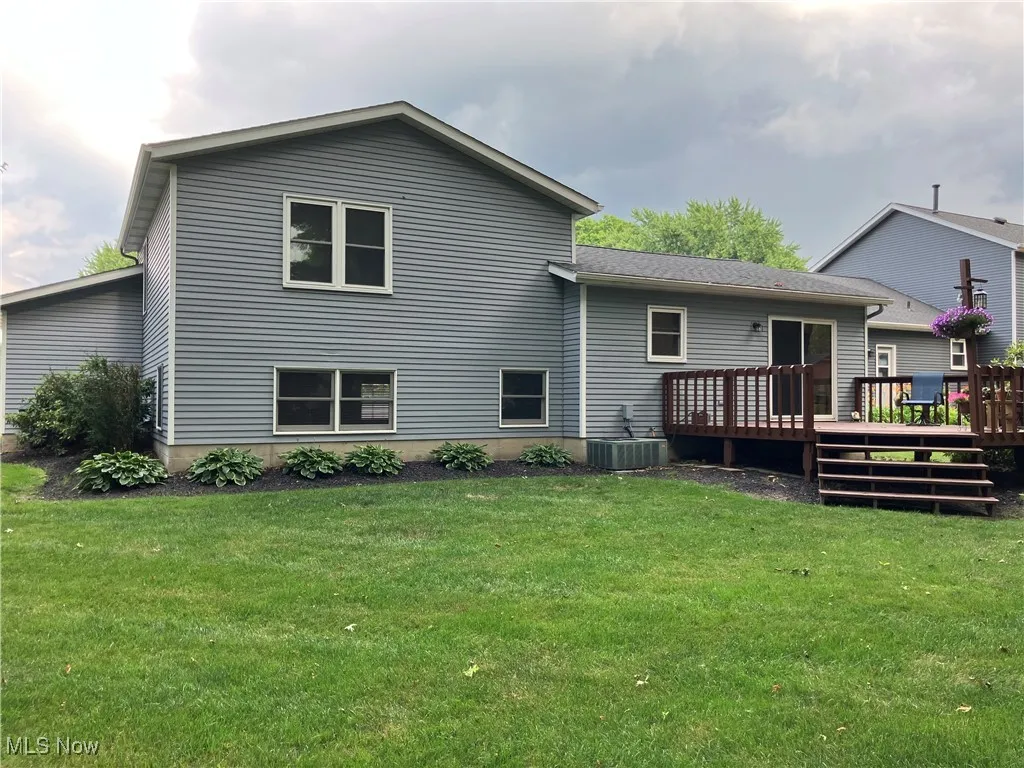Back of house with a deck and a lawn