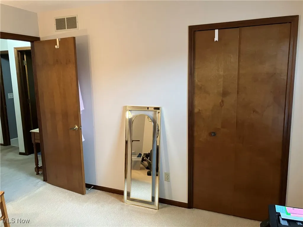 Unfurnished bedroom with light carpet and baseboards
