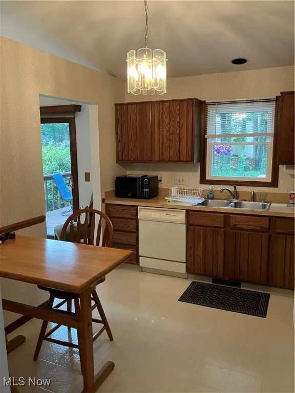 Kitchen featuring dishwashing machine, light countertops, black microwave, and a chandelier