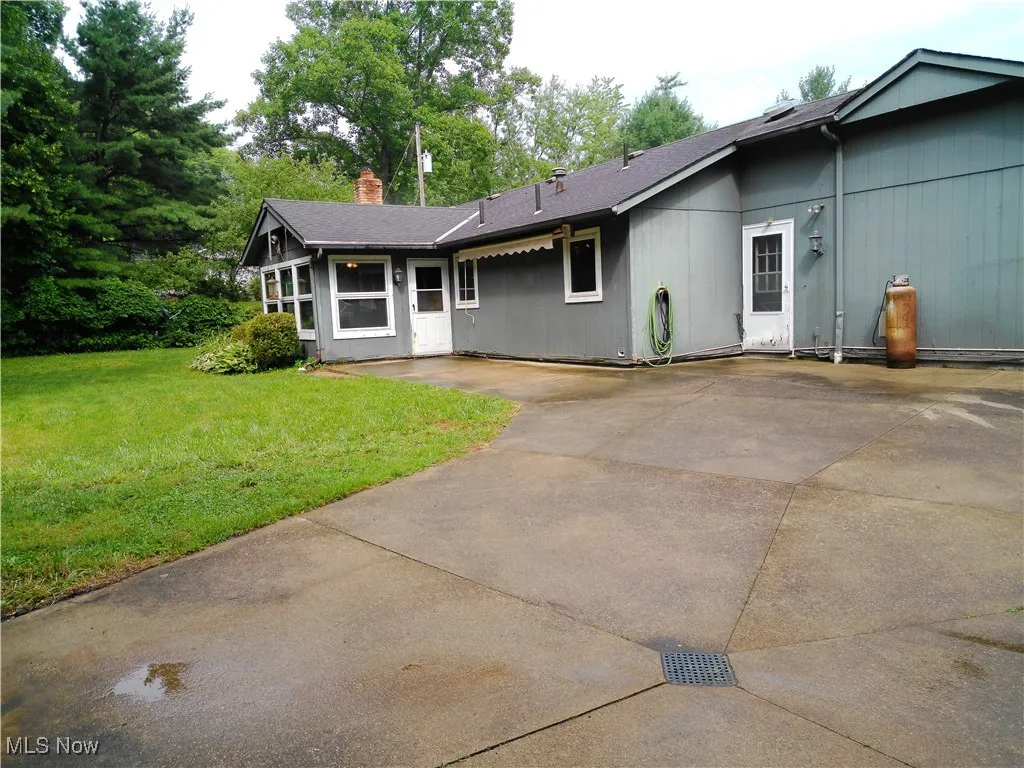 View of front of home featuring a chimney, a front yard, and concrete driveway