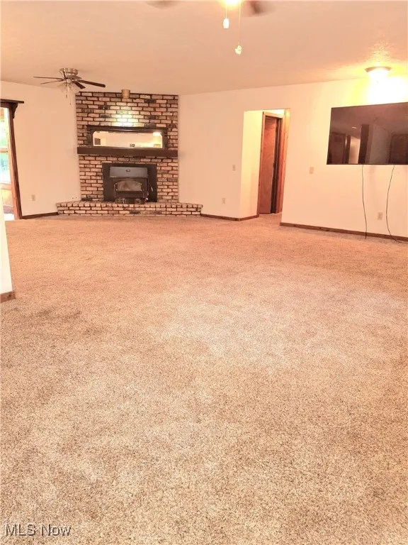 Unfurnished living room with a ceiling fan and light carpet