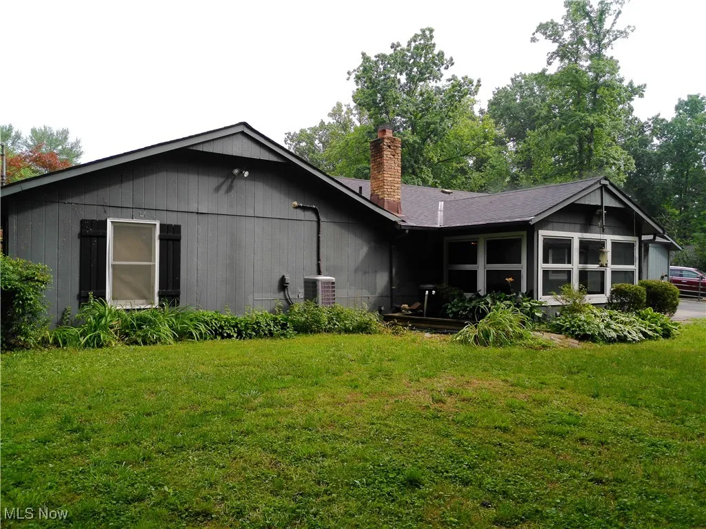 Back of house with a chimney and a yard