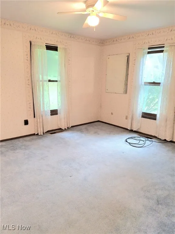 Spare room featuring light carpet, ceiling fan, and wallpapered walls